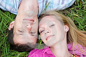 Young love couple lay on the green grass outdoors.