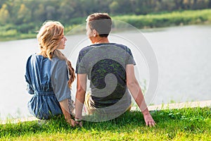 Young love couple sitting on the river bank in summer