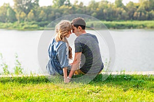 Young love couple sitting on the river bank in summer