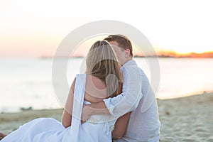 Young love couple sitting together on beach