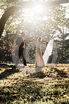 Young in love newly wed couple relaxing in field in golden afternoon sunlight