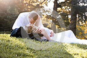 Young in love newly wed couple relaxing in field in golden afternoon sunlight