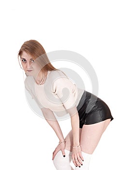 Woman standing in leather shorts bending forwards photo