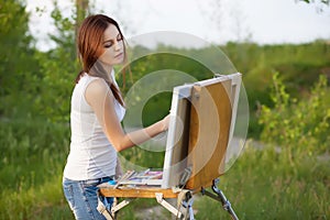 Young lovely caucasian woman painting outdoors