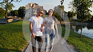 Young lovely couple having fun, playing, fooling in park in the summer. Warm sunny day. Full shot.