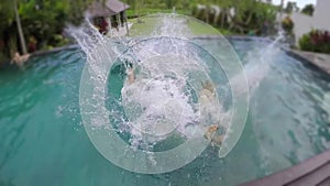 Young lovely couple photographed and fall into swimming pool at tropical vacation villa.