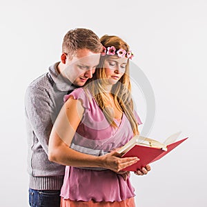 Young couple reading book together or looking at notes or drawings. Studio shot on white background