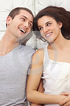 Young lovely couple together lying in a bed and listenning music