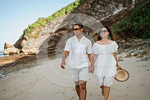 young lovely couple in white clothes hold hands walking stroll together at beach