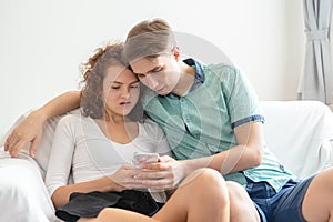 Young lover caucasion couple sitting and reading social news from mobile phone