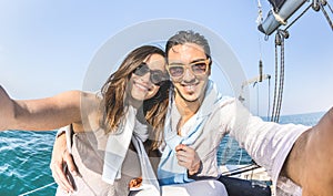 Young lover couple taking selfie on sailing boat tour around the world - Love concept at jubilee party cruise on luxury sailboat