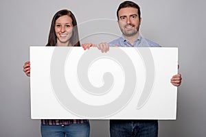 Young lovers couple holding a white cardboard