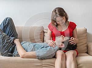 Young lovers - couple in love are relaxing on sofa and looking in eyes