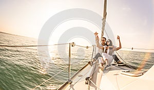 Young lovers couple on sail boat with champagne at sunset - Exclusive luxury concept with rich millennial people lifestyle on tour