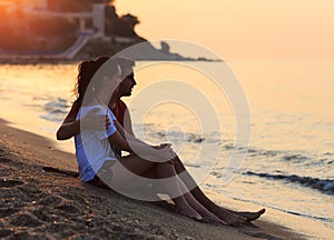 Young lovers sitting in the sand on shore