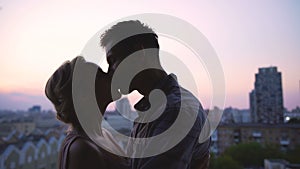 Young lovers tenderly enjoying each other against backdrop of beautiful sunset