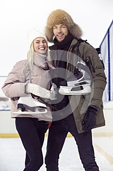 Young Loving  Caucasian Couple On Skatingrink With Ice Skates Posing Together Embraced Over a Snowy Winter Landscape