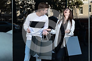 Young loving couple carrying shopping bags and laughing. Mock up. Black Friday. Shopping. Consumerism