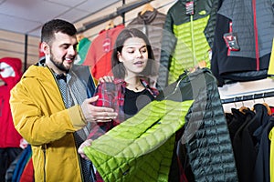 Young loving couple deciding on windcheater in store photo