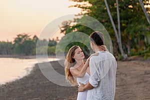 A young, loving couple embraces intimately, tender affection in a romantic, sun-dappled outdoor setting photo