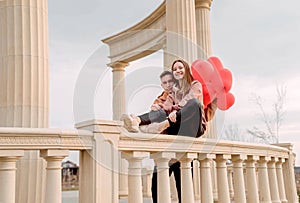 Young loving couple embracing each other outdoors in the park holding balloons