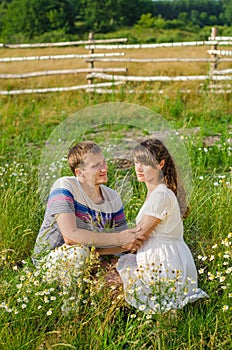 Young loving couple embracing each other sitting in the grass