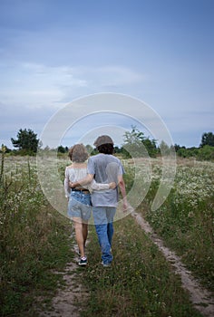 Young loving couple embracing strolls in the evening in the picturesque flowering fields