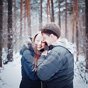 Young loving couple embracing in winter forest