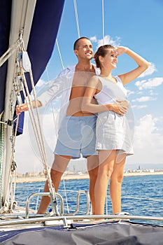 Young loving couple enjoying sea trip on pleasure sailboat along coast of Barcelona on sunny summer day