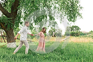 Young loving couple having fun and running on the green grass on the lawn with their beloved domestic dog breed Beagle and a