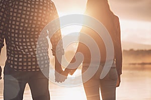 Young loving couple holding hands at sunset