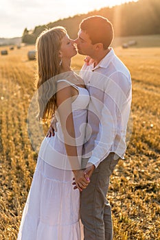 Young loving couple kissing in a field