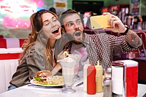 Young loving couple sit in retro bright cafe take a selfie