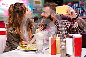 Young loving couple sit in retro bright cafe take a selfie