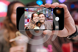 Young loving couple sit in retro bright cafe take a selfie