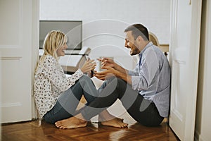 Young loving couple sitting on the floor with digital tablet