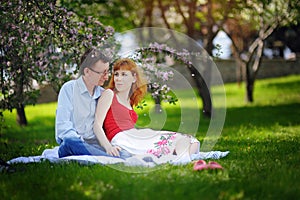 Young loving couple sitting at park on the grass in spring