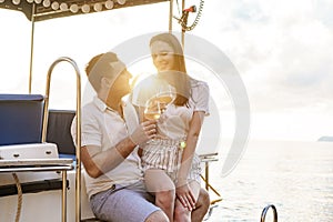 Young loving couple sitting on the yacht deck and drinking wine