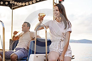 Young loving couple sitting on the yacht deck and drinking wine