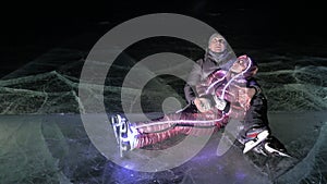 Young loving couple skating at ice rink at night. Man and woman kiss hug have fun learn to skate. Making love on ice
