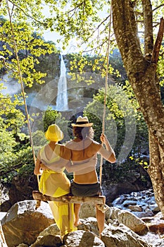 Young loving couple swing on a swing in the woods. Very romantic situation.