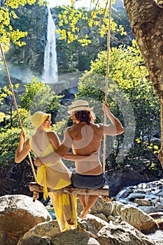 Young loving couple swing on a swing in the woods. Very romantic situation. It`s summer