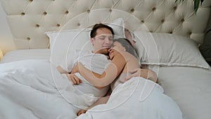 Young loving couple wake up in the morning. They kiss and hug his each other.