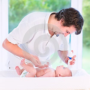 Young loving father changing diaper of his newborn baby son