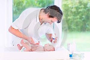 Young loving father changing diaper of newborn son