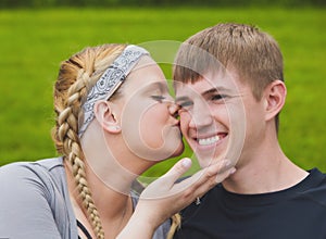 Young loving girl kissing her boyfriend on cheek