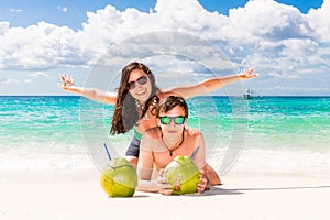 Young loving happy couple have fun on tropical beach, with coconuts. Summer vacation concept.