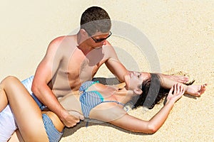 Young loving happy kissing couple on tropical beach, laying on s