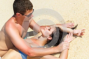 Young loving happy kissing couple on tropical beach, laying on s