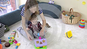 Young loving mom teaches daughter girl to distinguish object shapes.